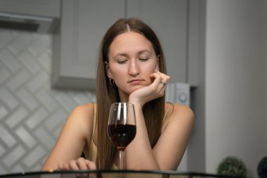 Zarif sarı elbiseler giyen çekici genç bir kadının portresi işten sonra evde dinlenen lezzetli kırmızı şarabın tadını çıkarıyor.