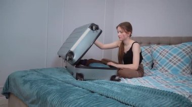 Yaz tatili gezisinden önce bavulda toplanıp bavullarını boşaltan mutlu genç kız. Seyahat Konsepti. dikey video