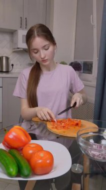 Genç Solak Genç Kız Ahşap Kesme tahtasında Taze Domatesleri Taze Dilimliyor, Besleyici Tabakları Çıtır Marul Yaprakları ve Soğanları Parlak Ev Yemeğiyle Hazırlıyor