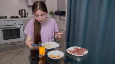 Rahat ev atmosferi, akıllı telefonuyla çalışırken yemekten zevk alan genç kız, yemek yerken birden fazla iş ve dijital iletişimin modern yaşam tarzını ön plana çıkarıyor.