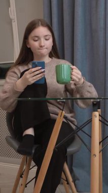 Genç kız dinleniyor, akıllı telefonla sohbet ediyor, sosyal medya uygulamalarına kayıyor, arkadaşlarına mesaj atıyor, ev ortamında rahat bir videoda çevrimiçi videolar izliyor.