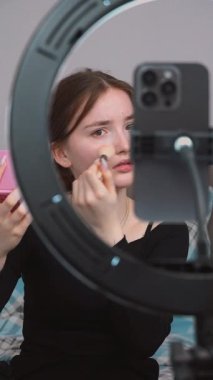 Genç vlogger çocuk kanalı için video blogu yapıyor. Güzellik blogları, teknoloji ve insanlar konsepti - mutlu gülümseyen kız blogcu, zil ışığı ve akıllı telefon ile evde dikey video uygulaması