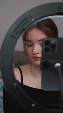 Genç vlogger çocuk kanalı için video blogu yapıyor. Güzellik blogları, teknoloji ve insanlar konsepti - mutlu gülümseyen kız blogcu, zil ışığı ve akıllı telefon ile evde dikey video uygulaması