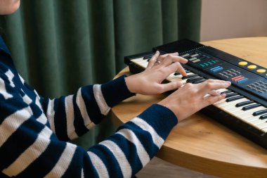 Klasik bir elektronik sentezleyici klavyesini ahşap bir masanın üstünde çalarken müzik besteleyen kadın müzisyen yaratıcılığı ve tutkuyu genel bir perspektiften yakalıyor.