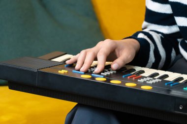 Bir müzisyenin elinin, klasik bir sentezleyici klavyesindeki ayarları ayarlarken, farklı sesleri keşfederken ve elektronik müzik yaratırken yakın plan çekimi.