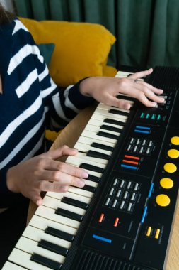 Klasik bir sentezleyici klavye kullanarak elektronik müzik besteleyen bayan müzisyen, nostalji ve sıcak bir ev ortamında retro seslere karşı bir tutku uyandırıyor. Dikey fotoğraf