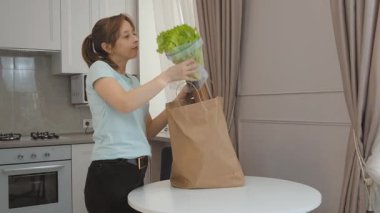 Mutfakta endişeli bir ifadeyle duran genç bir kadın, market fişini kontrol ediyor ve yüksek gıda fiyatlarının şokunu yaşıyor, artan yaşam maliyetlerinin ekonomik zorluklarını yansıtıyor