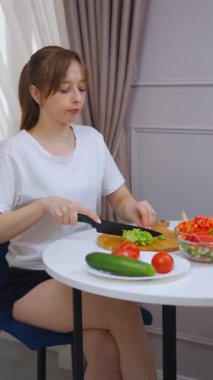 Profesyonel kadın aşçı, kırsal ahşap kesim tahtasının üzerinde gevrek yeşil marulu dikkatlice dilimliyor. Besleyici ev yapımı yemekler için hassasiyetle ve aşçılık uzmanlığıyla taze malzemeler hazırlıyor.