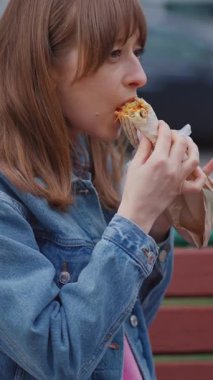 Güzel genç bir kadın ya da kız, işlek bir caddede bankta otururken lezzetli vejetaryen ya da vejetaryen kebap kebabı yiyor. Fast food ve abur cubur konsepti. Etik tüketim.