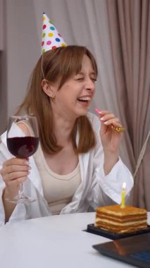 Genç bir kadın doğum gününü evde kutluyor, şenlikli parti şapkası takıyor, video görüşmesinde şarap içiyor, yakınları ve arkadaşlarıyla bilgisayar ekranı aracılığıyla iletişim kuruyor..