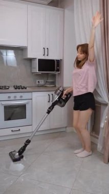 Evini temizlerken ya da ev işi yaparken müzik dinleyip dans eden pozitif bir genç kadın. Genç bir bayanla dans, mutluluk ve hijyen. Ev eşyaları ve ev eşyaları için.