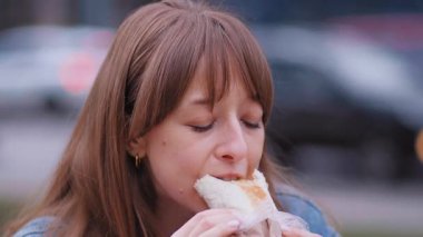 Şehir bankında oturan genç bir kadın öğle arasında hızlı ve sağlıklı sokak yemeklerinin tadını çıkarırken bir yandan da kendini şehir ortamına daldırarak ağız sulandıran shawarma yiyor.