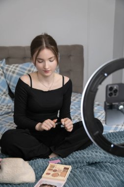 Genç nüfuzlu kişi, telefon ve telefon kullanarak bir video blogu kaydediyor, çevrimiçi dinleyicileriyle iletişim kuruyor ve güzellik veya yaşam tarzı ipuçları paylaşıyor.