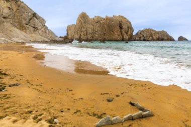 Altın kumun, kristal berraklığında turkuaz suların, yumuşak dalgaların, engebeli uçurumların ve yemyeşil çimlerin olduğu resimli bir sahil. Arnia Plajı, Liencres, Cantabria, İspanya.