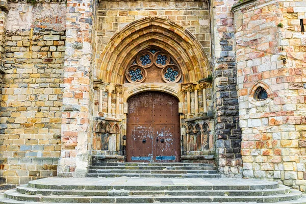 Santa Maria de la Asuncion Kilisesi 'nin kemerli girişi. Karmaşık detaylar ve dekoratif motiflerle süslenmiş taştan kapı aralığı. Castro-Urdiales, Cantabria, İspanya.