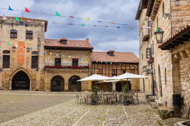 Şehrin kırsal kesimindeki eski evleri ve ortaçağ kalbiyle Plaza Mayor 'ın manzarası. Santillana del Mar, Cantabria, İspanya.