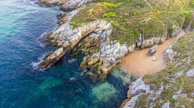 Virgen del Mar adasının kayalık sahil manzarası yeşil bitki örtüsü, terk edilmiş küçük bir sahil ve Atlantik Okyanusu suları ile kaplıdır. Cantabria, İspanya.