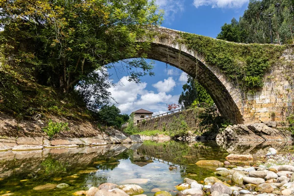 Miera Nehri üzerindeki Orta Çağ yaya köprüsü ve suya yansıyan mavi gökyüzü. Güneşli bir yaz günü. Lierganes, Cantabria, İspanya.