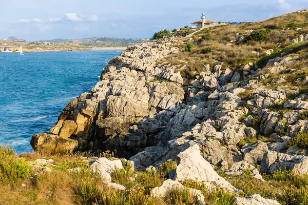 Punta del Torco Deniz Feneri. Atlantik Okyanusu 'yla çevrili yüksek bir uçurumun tepesinde sıkışmış beyaz bir kule. Takım elbiseler, Cantabria, İspanya.