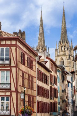 Kırmızı panjurları, caddesi ve arka planda Sainte-Marie Katedrali kuleleri olan geleneksel yarı keresteli evler. Bayonne, Pirenes-Atlantik, Fransa.