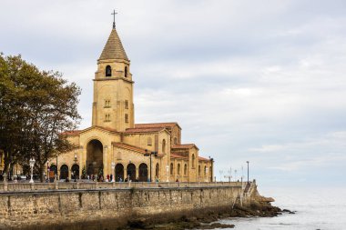 Campo Valdes 'teki San Pedro Kilisesi' nin manzarası, Roma öncesi mimariden esinlenilmiş tarihçi tarzda bir Katolik tapınağı, deniz kıyısı ve bulutlu bir günde okyanus. Gijon, Asturias, İspanya.