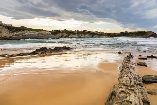 Stock image Portio Beach with its golden sand, layers of rock eroded since the Glaciation, the raging Atlantic Ocean, and looming storm clouds. Costa Quebrada Geopark, Cantabria, Spain.