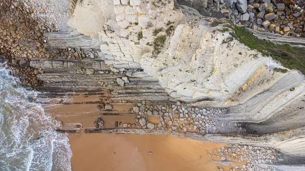 Sıra dışı kaya oluşumları ve katmanlı kayadan yapılmış keskin beyaz kayalıkları olan Portio Beach 'in yukarıdan aşağı manzarası. Costa Quebrada Geopark, Cantabria, İspanya.