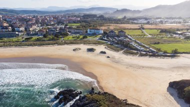 Ris Sahili 'nin havadan görünüşü, kumlu kıyıları Atlantik' le çevrili. Yeşil tarlalar, Noja köyü ve uzak dağlar cennet manzarasını tamamlıyor. Noja, Cantabria, İspanya.