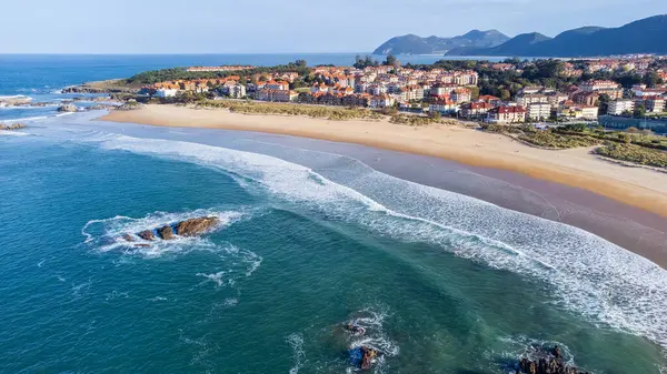 Kumlu Ris Sahili, Atlantik Okyanusu dalgaları, adacıklar, Noja köyü ve uzak dağların hava manzarası. Noja, Cantabria, İspanya.