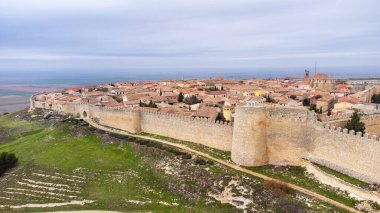 Tepedeki küçük, iyi korunmuş ortaçağ kasabası Uruea 'nın panoramik manzarası. Kasaba kale duvarı, kapılar ve arkalarındaki şehir. Uruena, Valladolid Eyaleti, Kastilya ve Leon, İspanya.