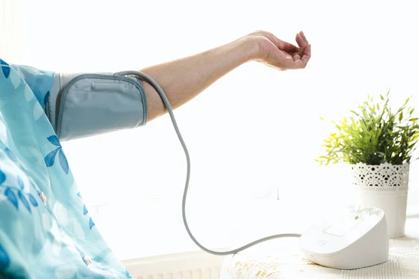 Senior woman examining her blood pressure on her arm