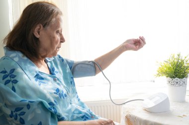 Senior woman examining her blood pressure on her arm