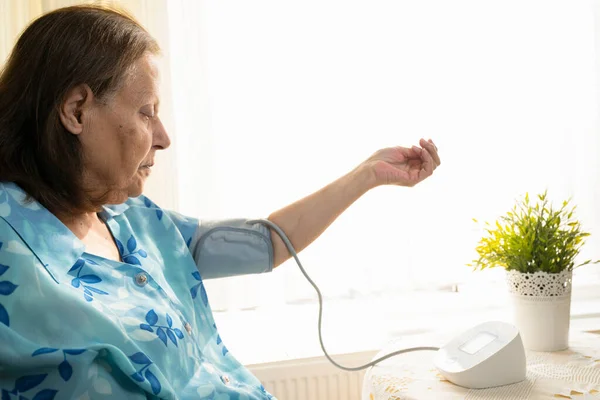 Senior woman examining her blood pressure on her arm