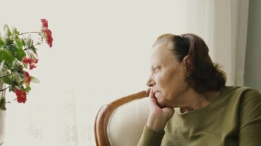 Koltukta oturan düşünceli yaşlı kadın.