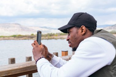 Akıllı telefon kullanan yakışıklı Afro-Amerikan adamın portresi.