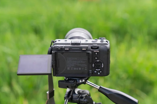 professional video camera with a tripod on the background of the grass