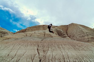 Afrikalı bir adam dağın tepesine atlıyor.