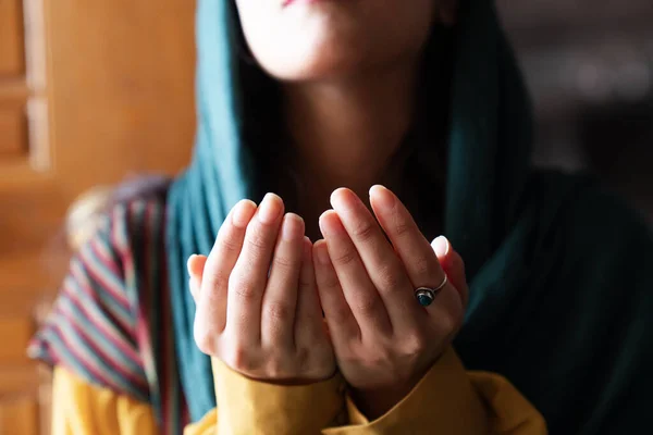 Muslim woman in headscarf and hijab prays with her hands up in air in mosque.Religion praying concept.