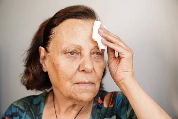 senior woman sweating suffering heat stroke at home