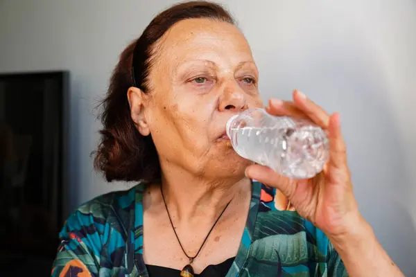 Close-Up Portrait Of A Elderly Woman Drinking Water