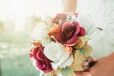 Gelin elinde çiçek buketi tutuyor. Gelin ve düğün buketi