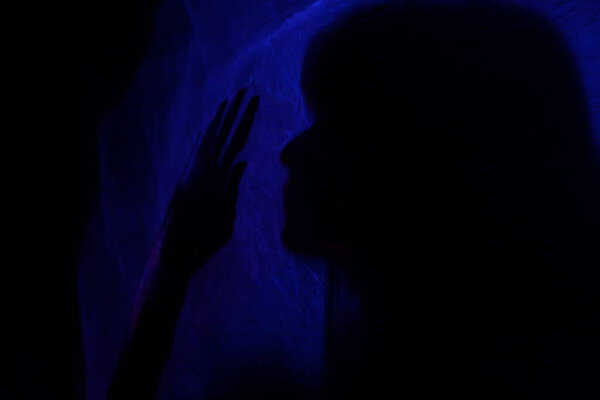 Силуэт женщины за синим светом представляет таинственно и художественно