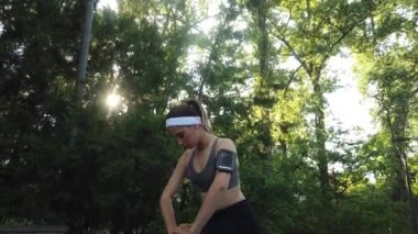 Parkta koşuya çıkan genç bir kadın, ağaçların arasından güneş ışığı parlıyor.