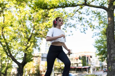 Sokakta koşan kadın kulaklık takıyor.