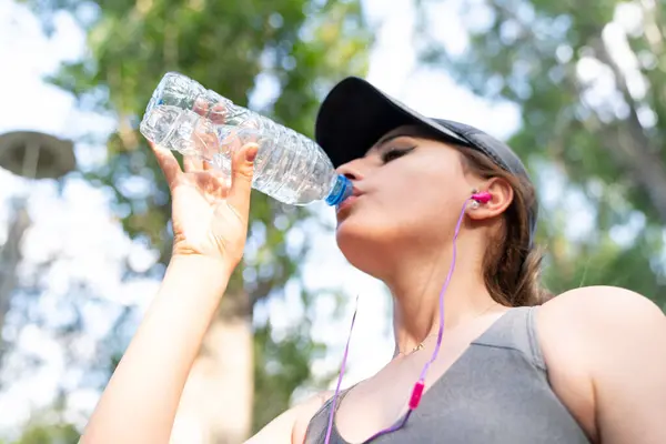 Woman drinking water after hard workout in the park.