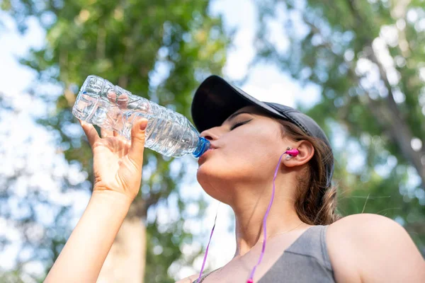 Woman drinking water after hard workout in the park.