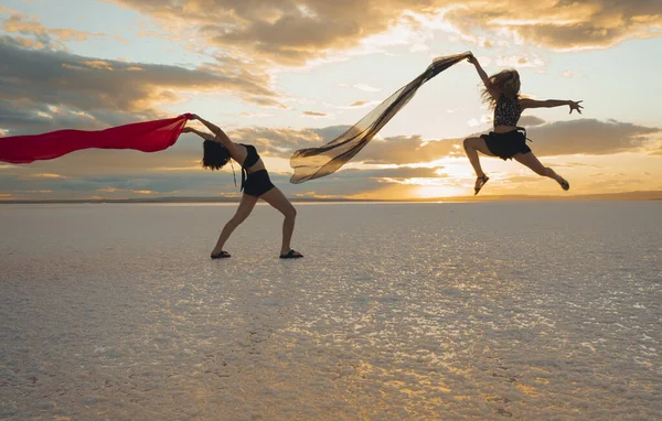 two women gracefully dances on the beach by the sea on a summer day