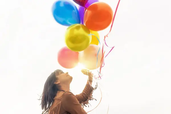 Young woman holding a bunch of balloons