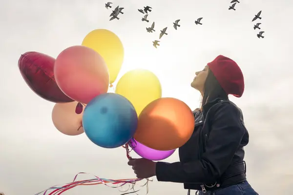 Young woman holding a bunch of balloons , free and beauty.