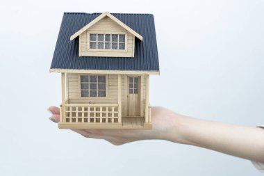 Beyaz arka planda izole edilmiş bir ev modeli tutan beyaz bir kadın.
